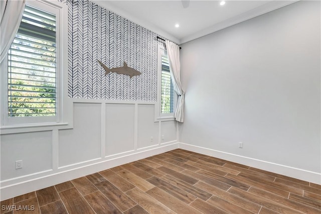 empty room featuring an accent wall, wood finished floors, a decorative wall, and baseboards