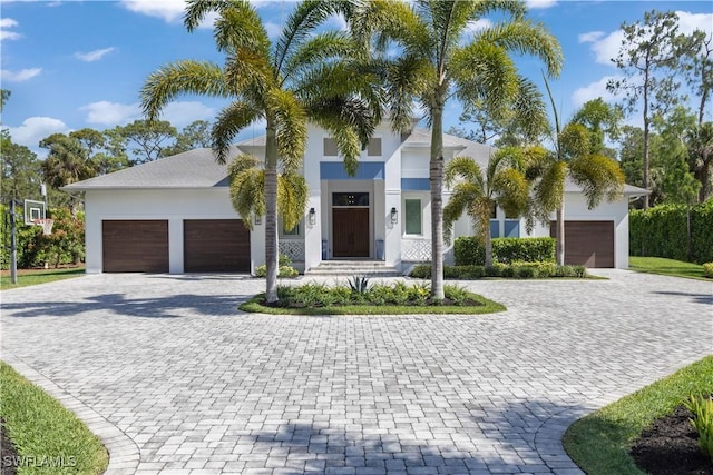 view of front facade featuring stucco siding, an attached garage, and decorative driveway