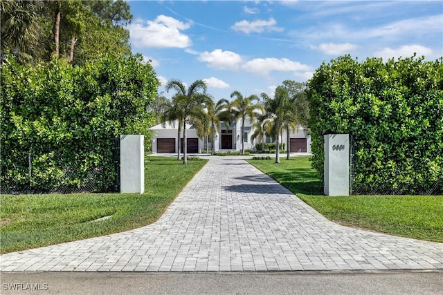 view of community featuring a yard and decorative driveway