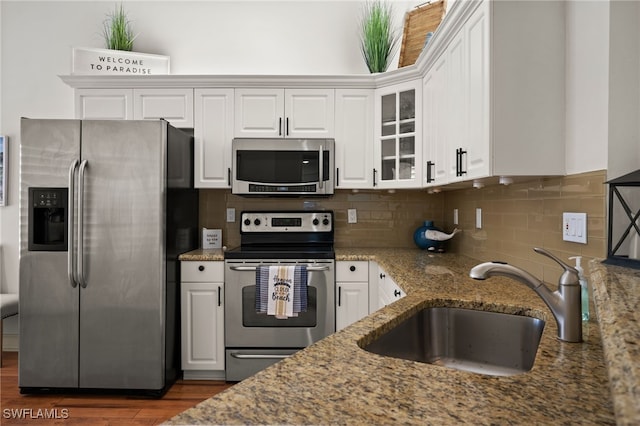 kitchen with stainless steel appliances, stone counters, a sink, and white cabinetry