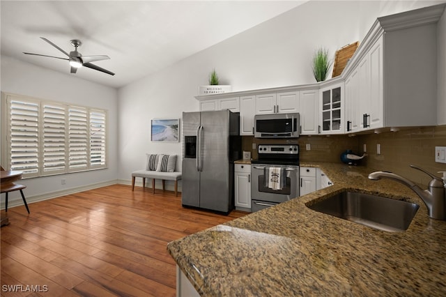 kitchen with backsplash, a ceiling fan, a sink, dark stone counters, and appliances with stainless steel finishes