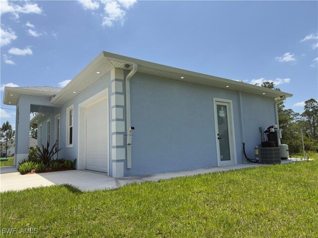 528 Aspen Ave S, Lehigh Acres, FL 33974 - view of home's exterior featuring stucco siding, a garage, concrete driveway, and a yard