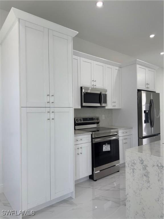 528 Aspen Ave S, Lehigh Acres, FL 33974 - kitchen featuring appliances with stainless steel finishes, recessed lighting, light marble finish flooring, white cabinetry, and light stone counters