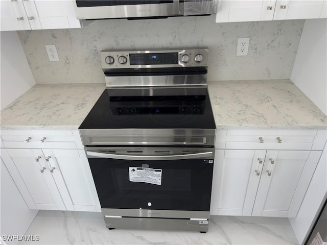 528 Aspen Ave S, Lehigh Acres, FL 33974 - kitchen featuring stainless steel range with electric stovetop, backsplash, white cabinetry, and light stone countertops