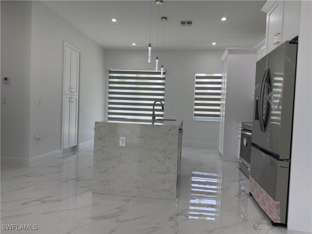 528 Aspen Ave S, Lehigh Acres, FL 33974 - kitchen with stainless steel refrigerator with ice dispenser, light marble finish flooring, recessed lighting, white cabinets, and decorative light fixtures