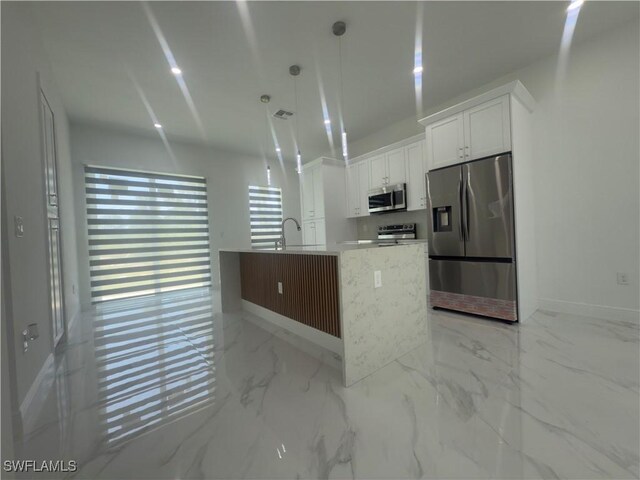 528 Aspen Ave S, Lehigh Acres, FL 33974 - kitchen with stainless steel appliances, white cabinets, baseboards, a kitchen island with sink, and a sink