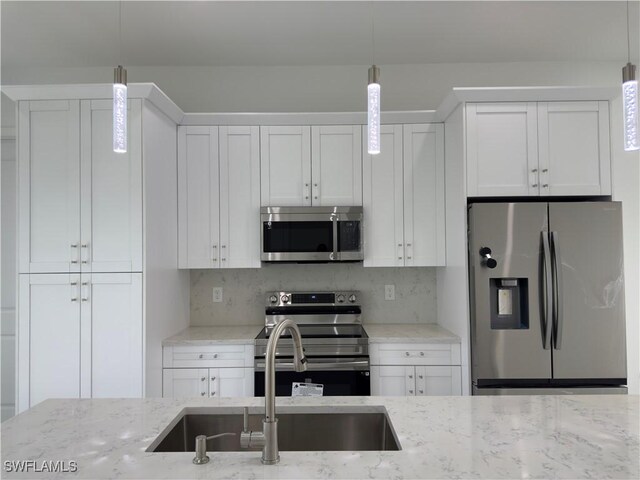 528 Aspen Ave S, Lehigh Acres, FL 33974 - kitchen featuring stainless steel appliances, a sink, white cabinetry, and pendant lighting