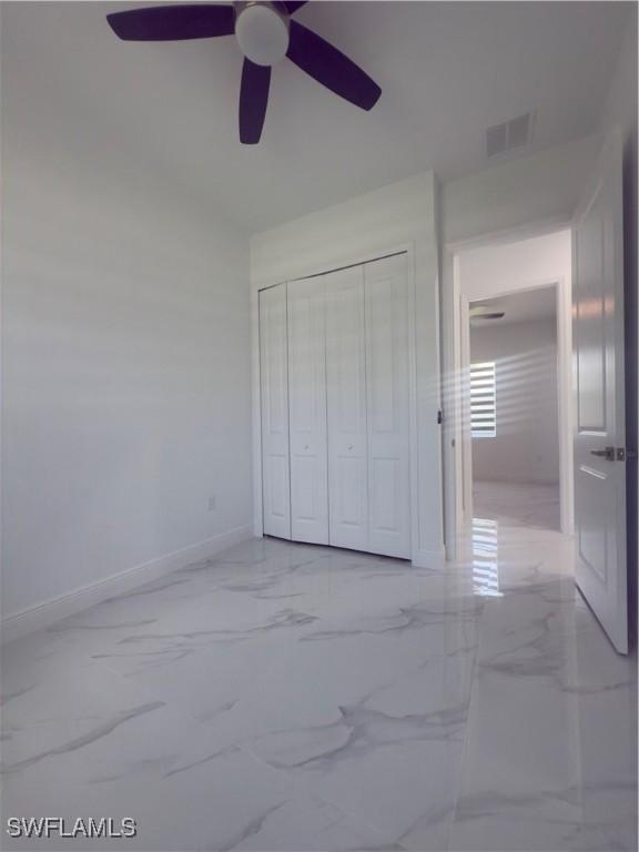 528 Aspen Ave S, Lehigh Acres, FL 33974 - unfurnished bedroom with marble finish floors, baseboards, a closet, and a ceiling fan