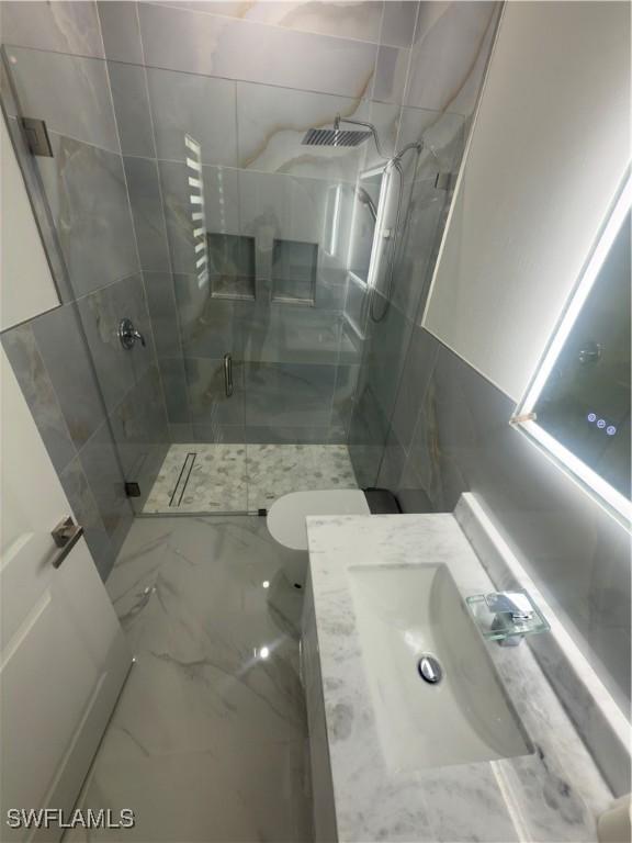 528 Aspen Ave S, Lehigh Acres, FL 33974 - bathroom featuring a shower stall, vanity, marble finish floors, and toilet