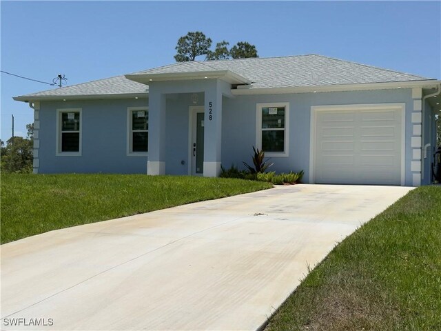 528 Aspen Ave S, Lehigh Acres, FL 33974 - view of front facade featuring concrete driveway, stucco siding, a front yard, an attached garage, and roof with shingles