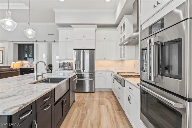 2008 SW 44th Ter, Cape Coral, FL 33914 - kitchen featuring stainless steel appliances, wall chimney range hood, white cabinets, a sink, and crown molding