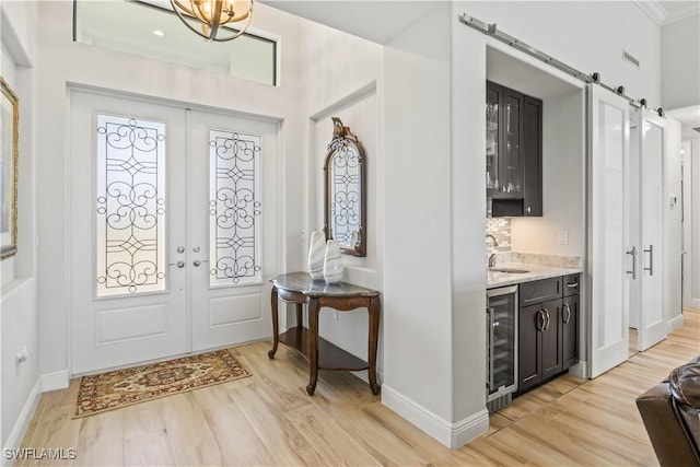 2008 SW 44th Ter, Cape Coral, FL 33914 - entrance foyer featuring beverage cooler, light wood-type flooring, a barn door, french doors, and ornamental molding