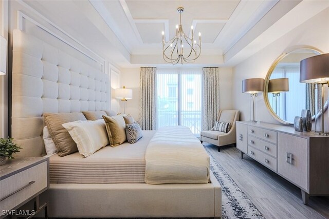bedroom featuring wood finished floors, a chandelier, and a tray ceiling