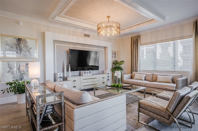 living room featuring a chandelier, visible vents, wood finished floors, and a tray ceiling