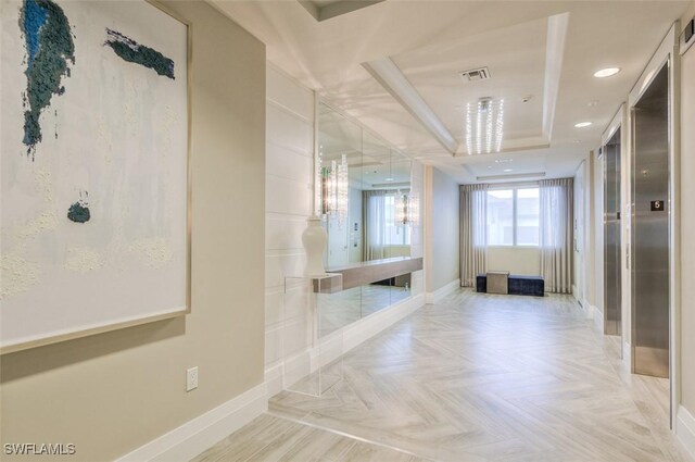 corridor featuring baseboards, recessed lighting, visible vents, and a tray ceiling