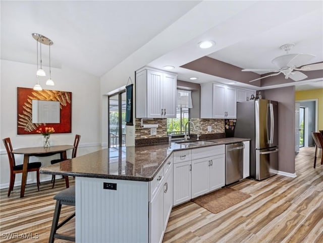 6030 Birnam Wood Ln, Fort Myers, FL 33908 - kitchen with tasteful backsplash, a sink, a breakfast bar, stainless steel appliances, and white cabinets