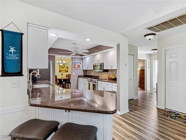 6030 Birnam Wood Ln, Fort Myers, FL 33908 - kitchen featuring visible vents, a sink, a peninsula, appliances with stainless steel finishes, and white cabinetry