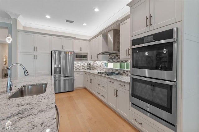 16733 Gilroy St, Bonita Springs, FL 34135 - kitchen featuring appliances with stainless steel finishes, a sink, wall chimney range hood, backsplash, and light wood-style flooring