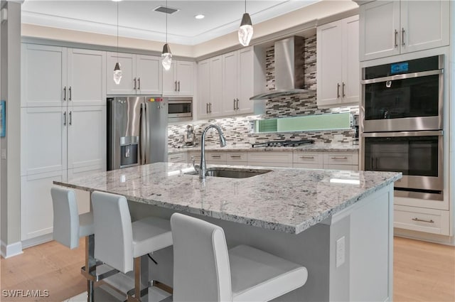 16733 Gilroy St, Bonita Springs, FL 34135 - kitchen featuring appliances with stainless steel finishes, a sink, wall chimney exhaust hood, light wood finished floors, and recessed lighting