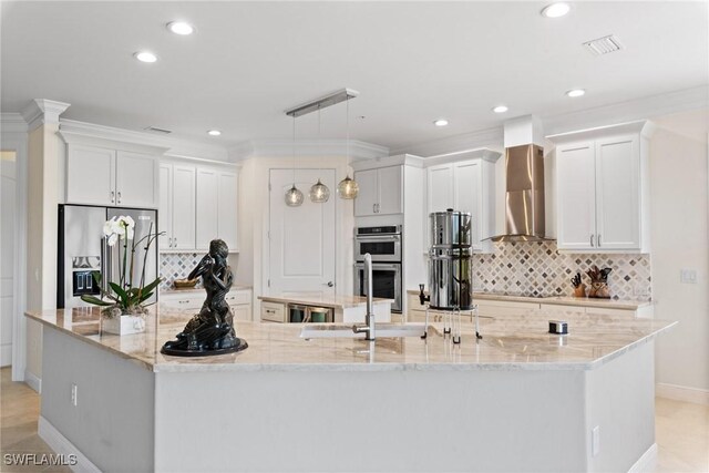 18580 Sandalwood Pointe Unit 101, Fort Myers, FL 33908 - kitchen featuring tasteful backsplash, a spacious island, visible vents, wall chimney range hood, and appliances with stainless steel finishes