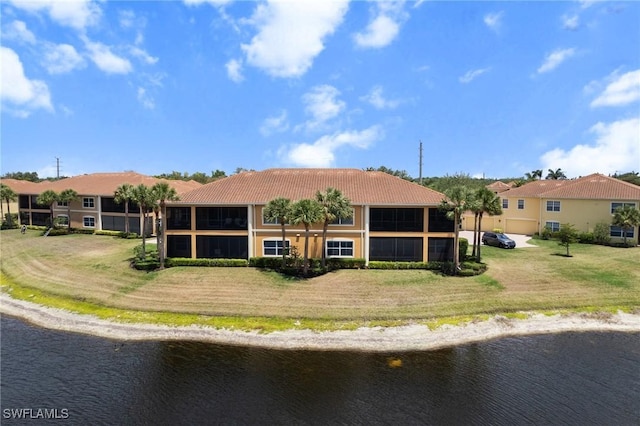 18580 Sandalwood Pointe Unit 101, Fort Myers, FL 33908 - back of house featuring a water view, driveway, a tiled roof, and a lawn