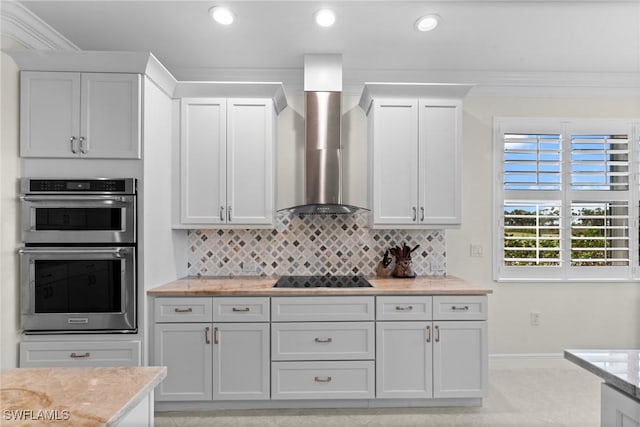 18580 Sandalwood Pointe Unit 101, Fort Myers, FL 33908 - kitchen with black electric stovetop, stainless steel double oven, wall chimney range hood, backsplash, and baseboards