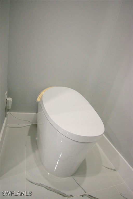 bathroom featuring baseboards, toilet, and marble finish floor