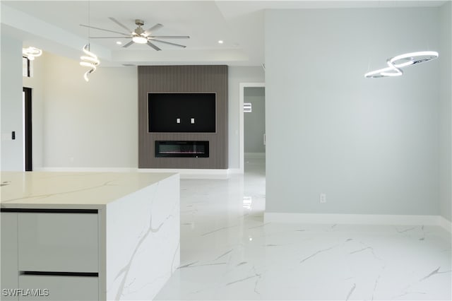 kitchen featuring a ceiling fan, baseboards, light stone counters, and marble finish floor