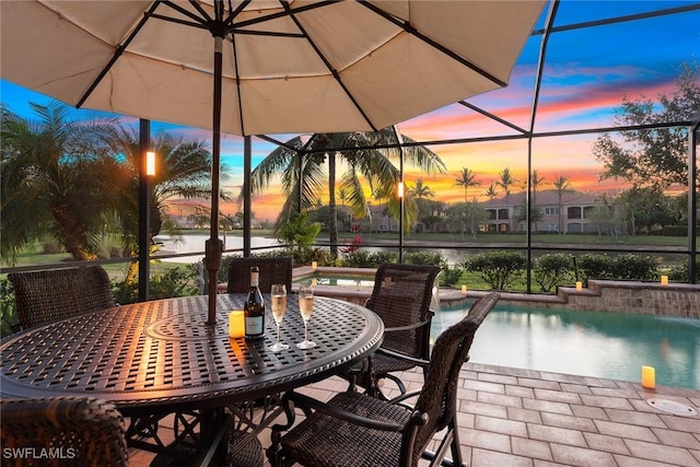 view of patio with glass enclosure, a water view, outdoor dining space, and an outdoor pool