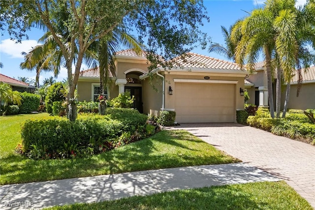 mediterranean / spanish-style house with stucco siding, an attached garage, decorative driveway, and a tile roof