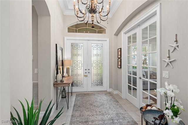 foyer with crown molding, french doors, arched walkways, light tile patterned floors, and a notable chandelier