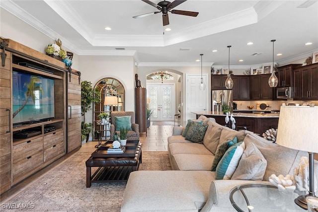 living area with crown molding, ceiling fan, arched walkways, recessed lighting, and a tray ceiling