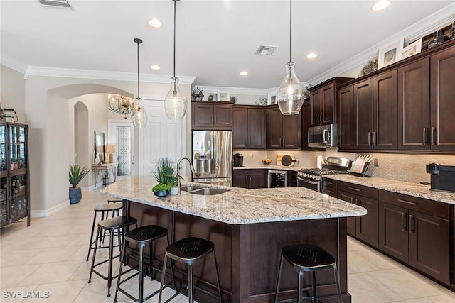 kitchen featuring visible vents, arched walkways, a kitchen breakfast bar, and stainless steel appliances