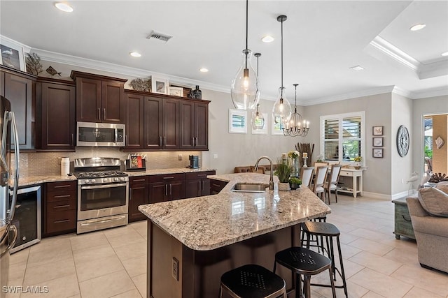 kitchen featuring visible vents, wine cooler, a sink, backsplash, and stainless steel appliances