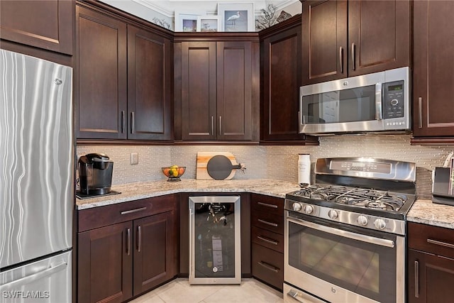 kitchen with appliances with stainless steel finishes, tasteful backsplash, light stone countertops, beverage cooler, and light tile patterned flooring