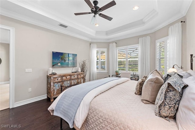 bedroom featuring visible vents, ornamental molding, wood finished floors, baseboards, and a raised ceiling