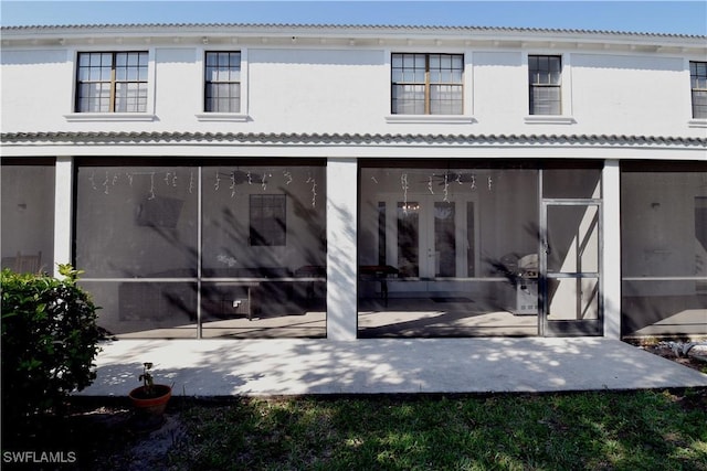 rear view of house with a patio area, a sunroom, and stucco siding