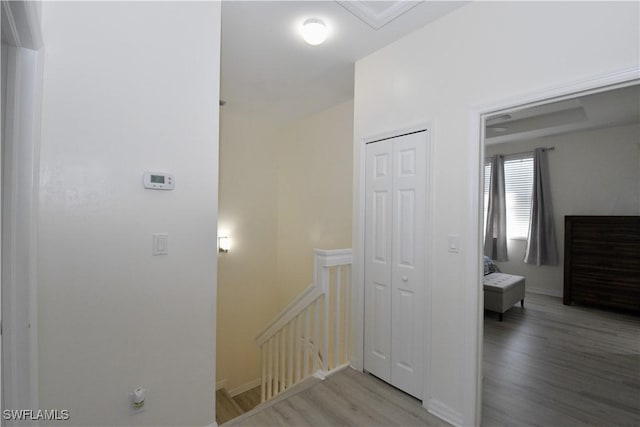 corridor with wood finished floors and an upstairs landing