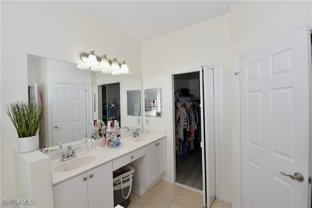 bathroom with a walk in closet, tile patterned flooring, a sink, and double vanity