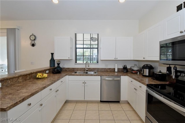 kitchen with a peninsula, a sink, white cabinetry, appliances with stainless steel finishes, and light tile patterned floors