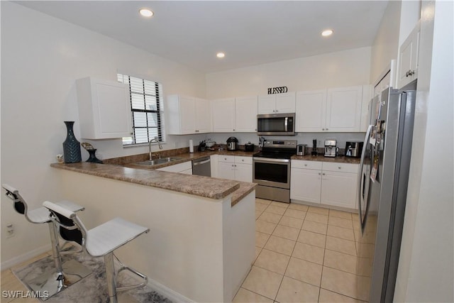 kitchen with a sink, stainless steel appliances, white cabinets, a peninsula, and recessed lighting