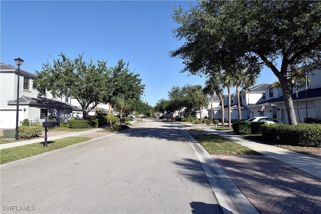 view of road featuring street lighting, sidewalks, a residential view, and curbs