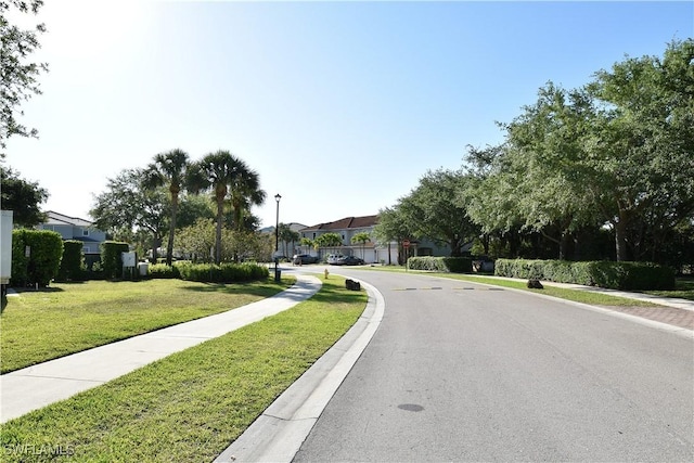 view of street featuring a residential view, sidewalks, curbs, and street lights