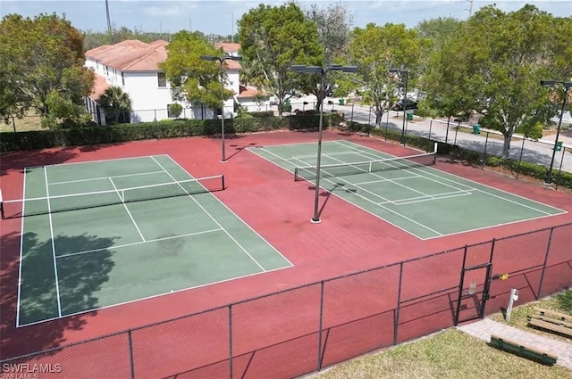 view of tennis court with community basketball court and fence