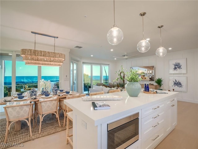 1072 S Seas Plantation Rd, Captiva, FL 33924 - kitchen featuring stainless steel microwave, white cabinets, light countertops, a center island, and open floor plan