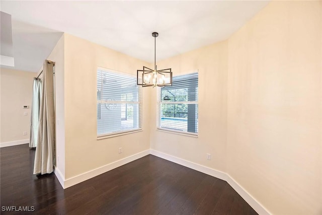 unfurnished dining area featuring dark wood finished floors, baseboards, and a chandelier