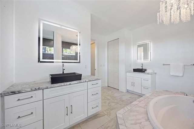 bathroom featuring two vanities, an inviting chandelier, marble finish floor, and a sink