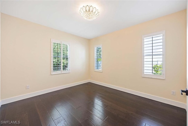 spare room featuring baseboards and dark wood-style flooring