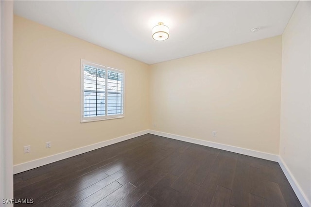 spare room featuring dark wood-type flooring and baseboards