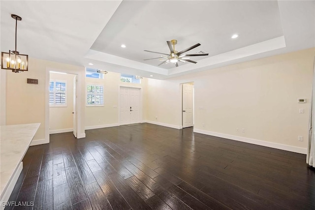 unfurnished living room featuring dark wood finished floors, baseboards, recessed lighting, ceiling fan with notable chandelier, and a raised ceiling